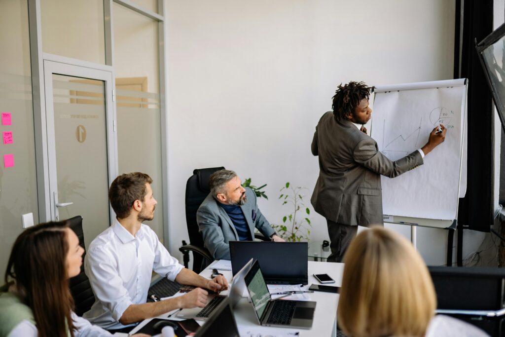 A diverse team in a modern office engaged in a strategic business meeting led by a presenter.